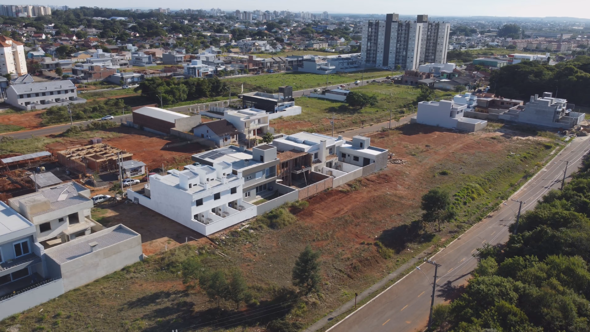 Vista aérea do Morada do Campus: lotes demarcados prontos para construir, com casas já erguidas e o centro de Canoas ao fundo